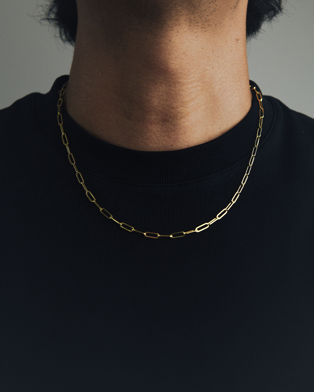 Hombre luciendo un collar de eslabones de oro amarillo de 14 quilates con una playera negra.