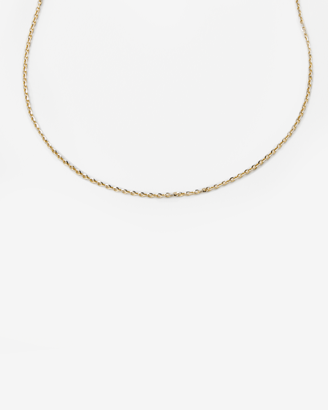 Cadena bicolor de oro blanco y oro amarillo con eslabones finos, fotografiada sobre un fondo blanco con un estilo minimalista. La cadena de 14 quilates forma una curva suave que destaca el contraste entre ambos tonos de oro y su acabado pulido, aportando un diseño elegante y versátil.