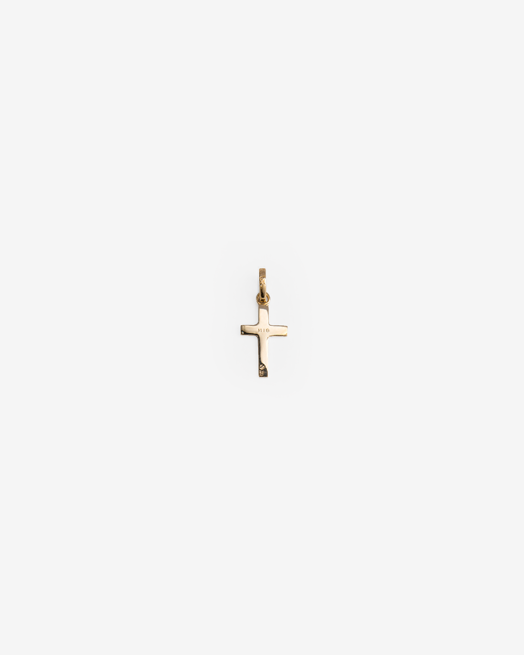 Primer plano del grabado M18 en un dije en forma de cruz de oro amarillo de 10 quilates.
