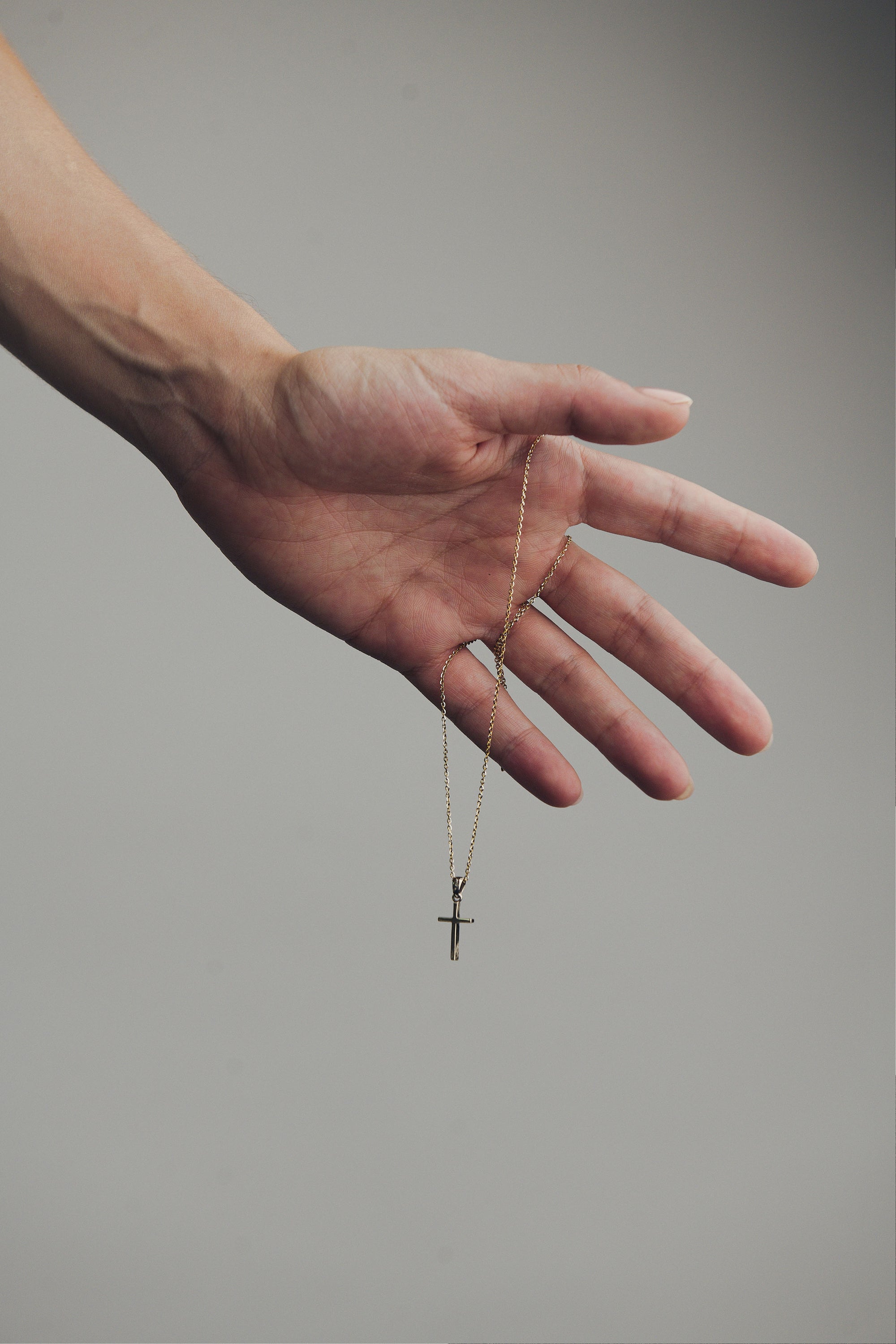 Mano con cadena bicolor y dije de oro blanco colgando, parte de la joyería de M18.