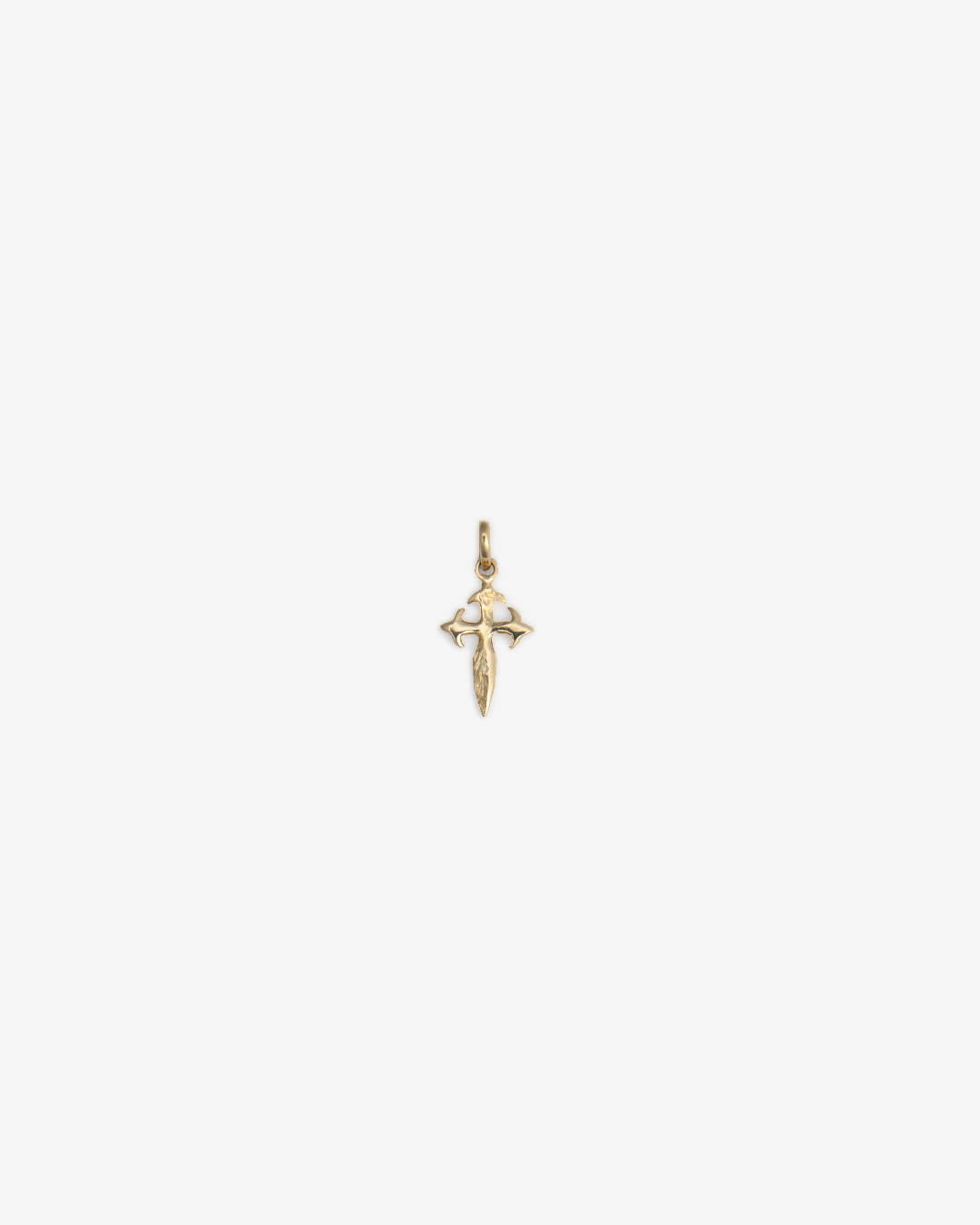 Dije de oro amarillo de 10 quilates en forma de cruz estilo medieval, fotografiado de frente sobre un fondo blanco.