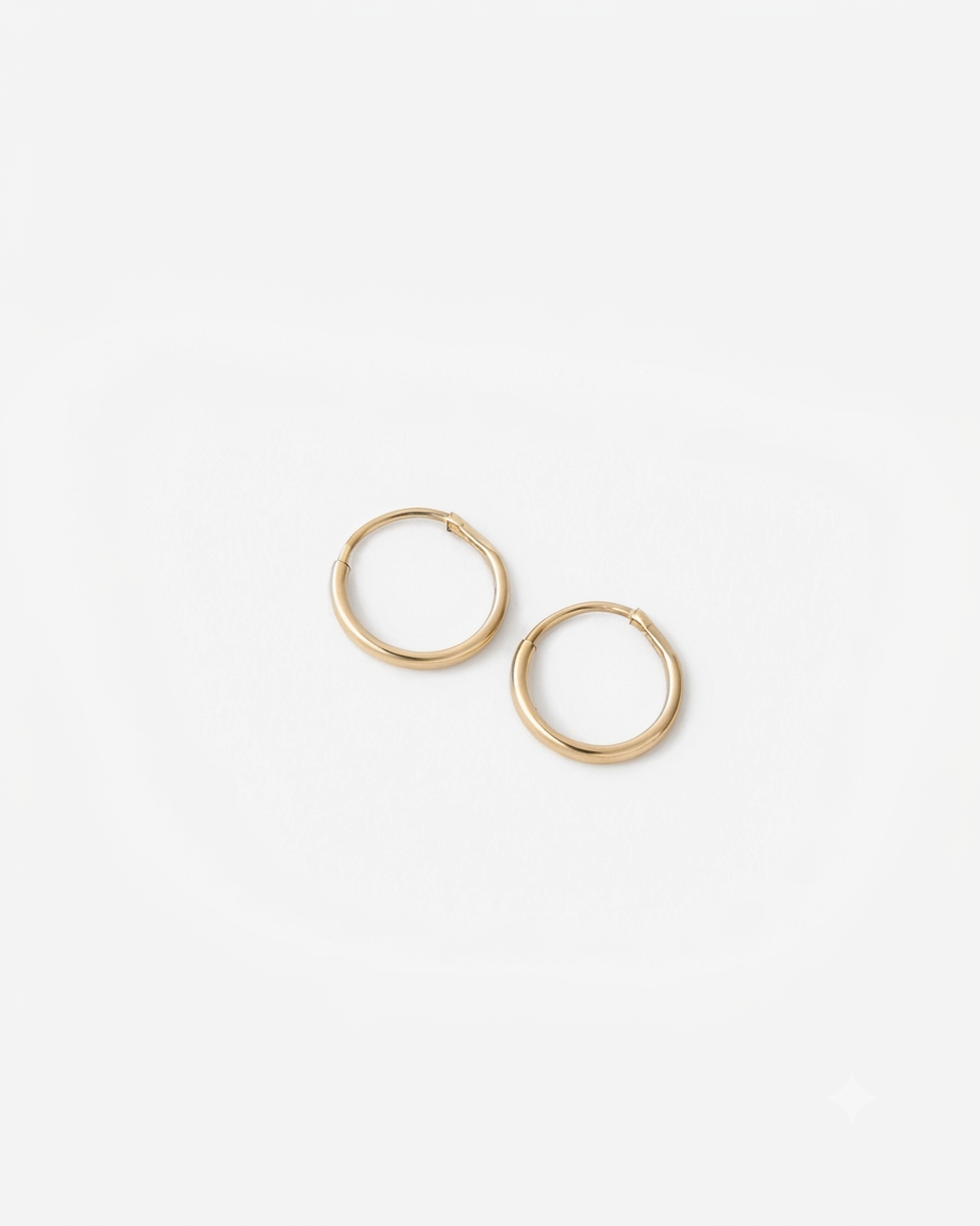 Mini hoops (arracadas pequeñas) de oro amarillo de 10 quilates sobre fondo blanco.
