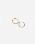 Mini hoops (arracadas pequeñas) de oro amarillo de 10 quilates sobre fondo blanco.